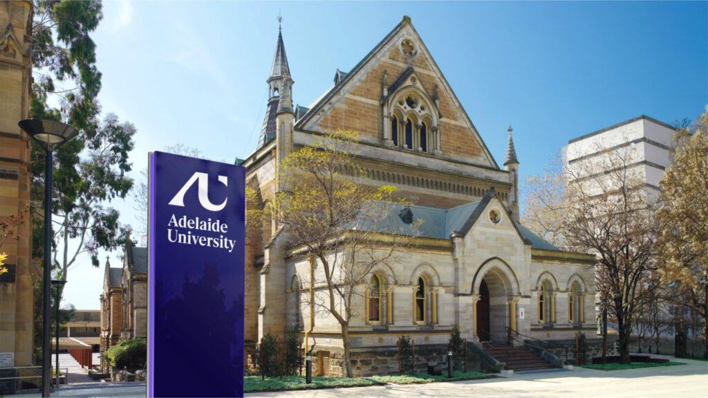 Adelaide University signage in front of a sandstone campus building